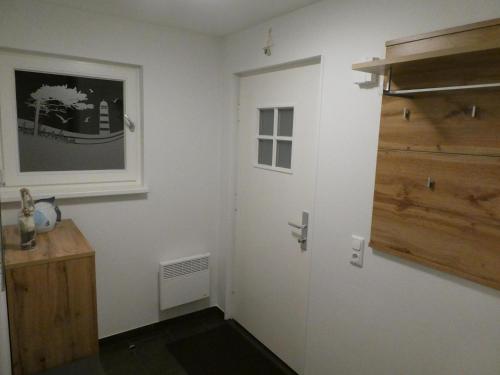 einen Flur mit einer weißen Tür und einem Holzschrank in der Unterkunft Ferienwohnung W18 1 S in Graal-Müritz