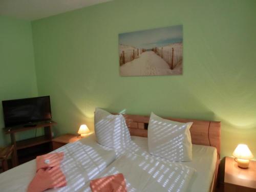 een slaapkamer met een bed met witte lakens en een televisie bij Ferienwohnung KK28 in Graal-Müritz