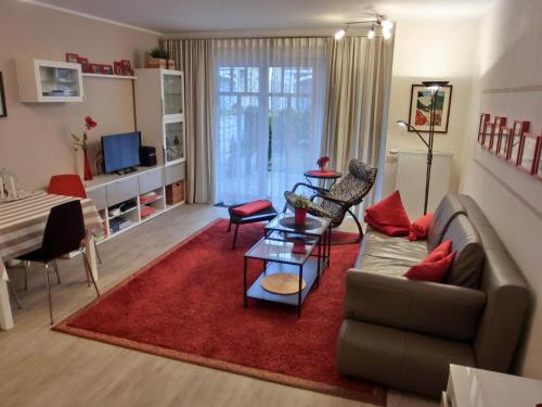 uma sala de estar com um sofá e um tapete vermelho em Ferienwohnung D1 em Graal-Müritz