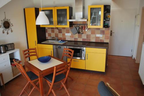 cocina con armarios amarillos, mesa y sillas en Ferienwohnung K38 "Sonnenblume", en Graal-Müritz