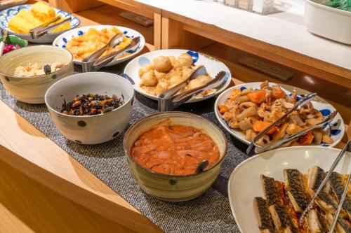 a table topped with bowls of different types of food at Hotel Liberte Asahikawa in Asahikawa