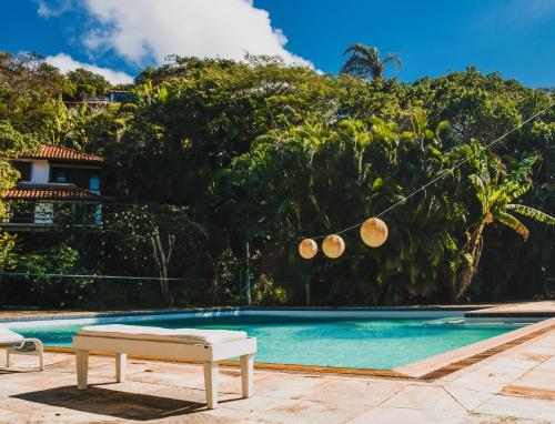 a swimming pool with a white bench next to a house at The Eco Palace Hostel in Búzios