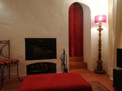 ein Wohnzimmer mit einem Kamin und einem roten Teppich in der Unterkunft Solar da Cavalariça in Ourique