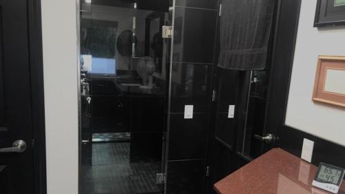 a glass shower door in a black bathroom at Shangri-La - Near Mendenhall Glacier and Auke Bay -DISCOUNTS ON TOURS! in Mendenhaven