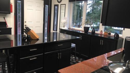 a kitchen with black cabinets and a counter with a window at Shangri-La - Near Mendenhall Glacier and Auke Bay -DISCOUNTS ON TOURS! in Mendenhaven
