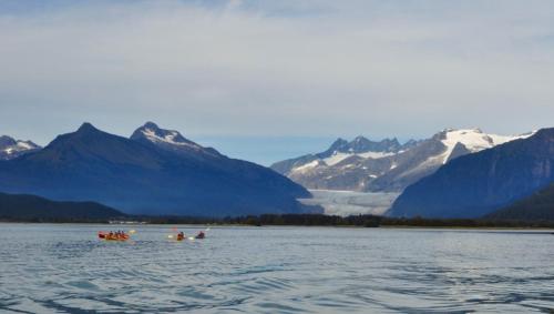 a group of people in kayaks on a lake with mountains at Glacier Guest Room - PRIVATE ROOM IN SHARED HOUSE REDUCED PRICE ON TOURS in Juneau