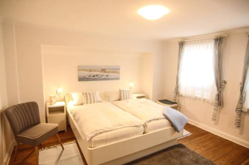 a bedroom with a bed and a chair and a window at Apartment Isermann 1 in Westerland (Sylt)
