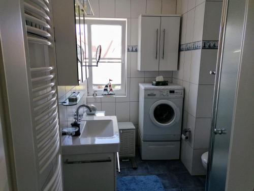 een kleine badkamer met een wasmachine en een wastafel bij Ferienwohnung M31 "Die Welle" in Graal-Müritz