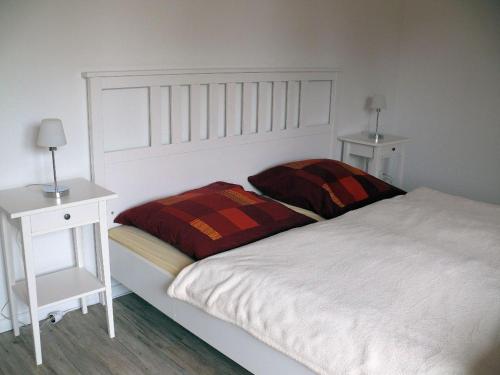 a white bed with two pillows and a night stand at Ferienwohnung P20 "Badenixe" in Graal-Müritz