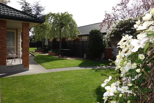 a house with a yard with white flowers at Northwood Motor Lodge in Christchurch