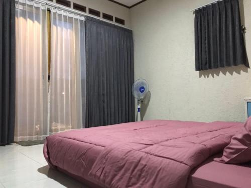 Schlafzimmer mit einem rosa Bett und einem Ventilator in der Unterkunft Saung Rancage Batukaras in Pangandaran