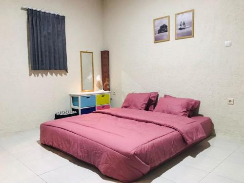 een slaapkamer met een groot bed en een roze deken bij Saung Rancage Batukaras in Pangandaran