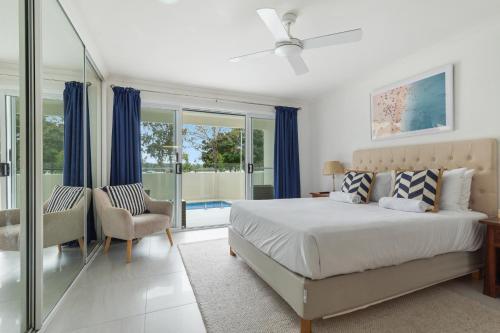 a bedroom with a bed and a chair and windows at Lazy Days 1 in Noosaville