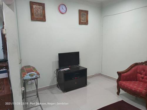 un soggiorno con TV e divano rosso di Teratak Port Dickson Homestay Mus Only a Port Dickson