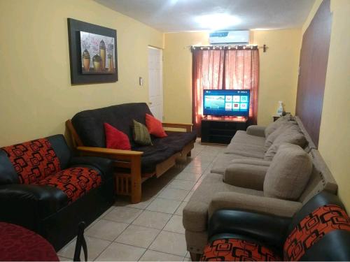 sala de estar con 2 sofás y TV en Casa Vicky Alojamiento para vacaciones y trámites consulares, en Ciudad Juárez