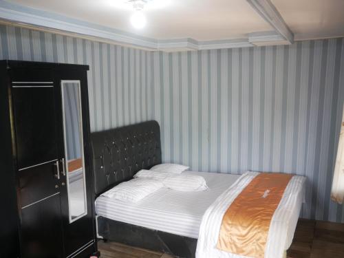 a small bed in a room with striped walls at Gunung Dago Resort Bogor Syariah in Bogor