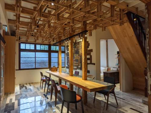uma sala de jantar com uma longa mesa de madeira e cadeiras em Spring12 House em Chiayi