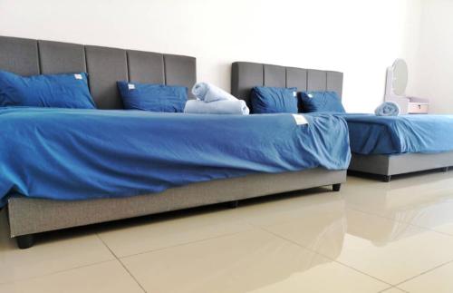 twee bedden met blauwe lakens en een knuffel erop bij Holiday Homestay Seremban in Seremban