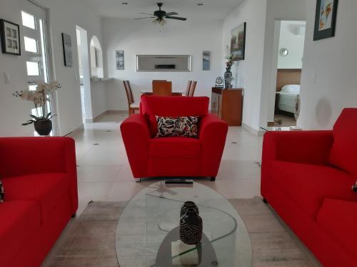 a living room with two red chairs and a glass table at Homecancun in Cancún