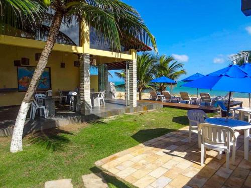 a resort with tables and chairs and blue umbrellas at Pousada Santo Aleixo in Porto De Galinhas