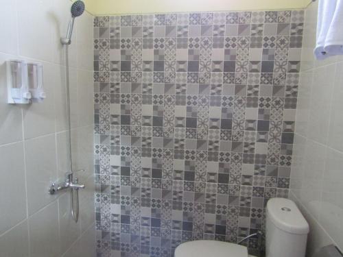 a bathroom with a toilet and a tiled wall at Anang Bed & Breakfast Syariah by Ndalem Beong in Magelang