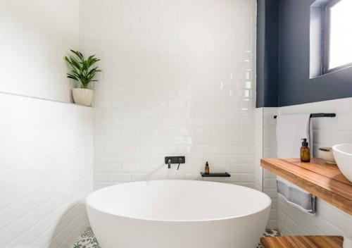 a white bathroom with a tub and a sink at Plett Holiday Stay with Pizza Oven and Views in Plettenberg Bay