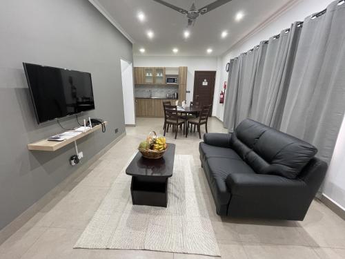 a living room with a black leather couch and a table at B Holiday Apartments in Beau Vallon