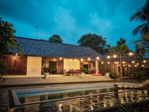 a villa with a swimming pool at night at Ndalem Treko Homestay in Magelang