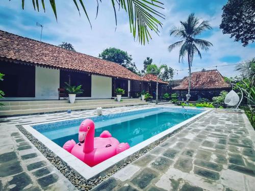 a pink float in the swimming pool of a villa at Ndalem Treko Homestay in Magelang