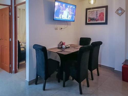 a dining room table with black chairs and a tv on the wall at Full apartment independent entrance, services included in Lima