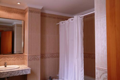 y baño con cortina de ducha y lavamanos. en Hotel Tio Felipe, en Carboneras