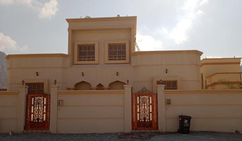 a large white house with orange gates at Ahlam Musandam Villa in Khasab