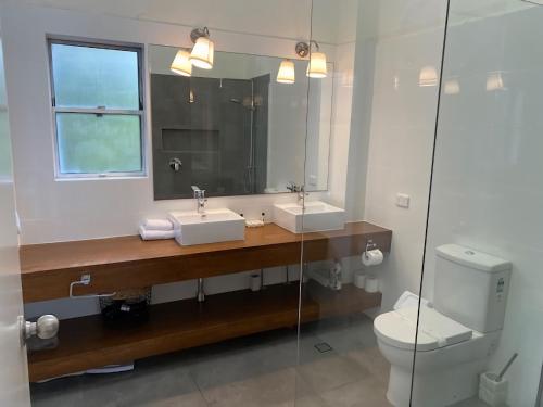 a bathroom with a sink and a toilet and a mirror at Little Cove Townhouse 2 Pandanus Street 14 in Noosa Heads