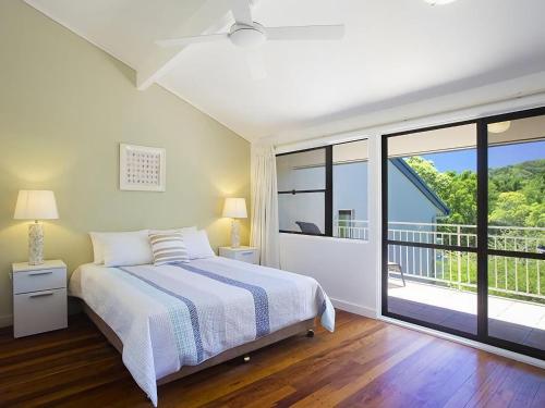 ein Schlafzimmer mit einem Bett und einem Balkon in der Unterkunft Little Cove Townhouse 5 Pandanus Street 14 in Noosa Heads