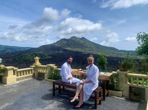 a man and a woman sitting at a table on a balcony at Ayodya Batur Villa in Kintamani