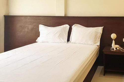 a bed with two white pillows and a wooden headboard at Bromo 22 Homestay Syariah near Terminal Bayuangga Probolinggo Mitra RedDoorz in Pilang