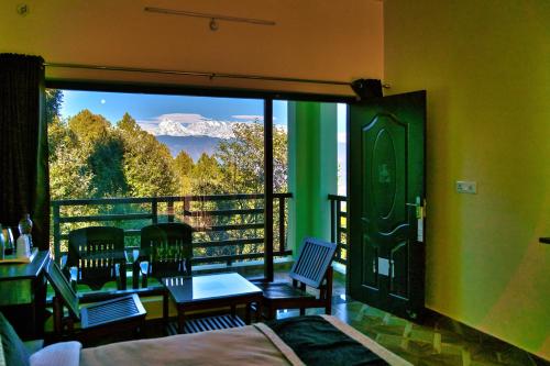 a room with a balcony with a view of a mountain at Himalaya Darshan Resort in Kausani