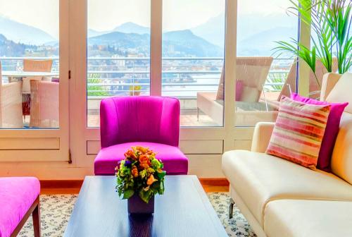 a living room with pink chairs and a table with a vase of flowers at Suitenhotel Parco Paradiso in Lugano