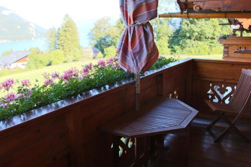 a porch with a bench and an umbrella and flowers at Ferienwohnung Schossleitner - der Wohlfühl-Ansitz am Wolfgangsee mit Weitblick in Sankt Gilgen