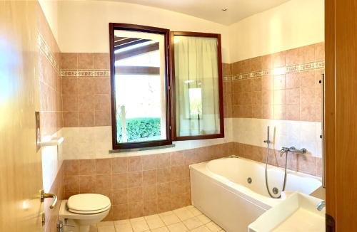 a bathroom with a tub and a toilet and a sink at Casa in Maremma Tuscany Village in Scarlino