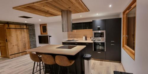 a kitchen with black cabinets and a island with bar stools at L'échappée belle Villaroger in Villaroger