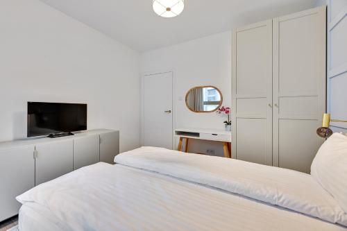 a white bedroom with a bed and a tv at GRANO APARTMENTS Gdańsk Old Town SPA & Wellness - GRANO APARTMENTS Gdańsk Residence SPA & Wellness in Gdańsk