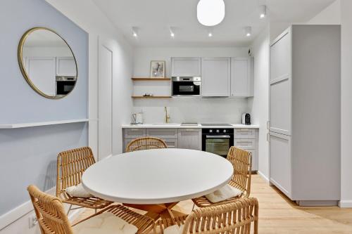 a white kitchen with a white table and chairs at GRANO APARTMENTS Gdańsk Old Town SPA & Wellness - GRANO APARTMENTS Gdańsk Residence SPA & Wellness in Gdańsk
