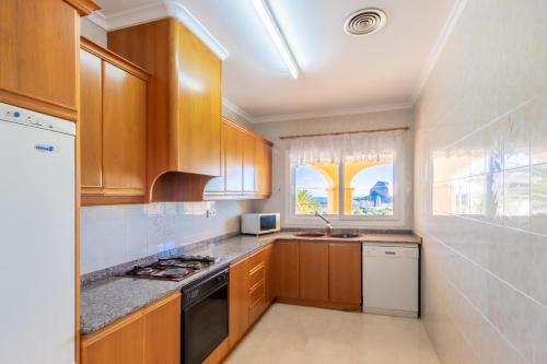 a kitchen with wooden cabinets and a window at Villa Cucarres in Calpe