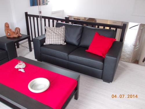 a living room with a black couch and a red table at In De Achtste Hemel in Schimmert