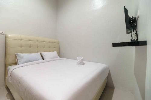 um quarto com uma cama branca e uma televisão em Homestay E Rahayu Anyer RedPartner em Serang