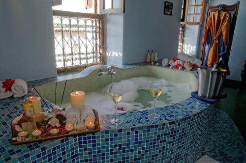 فندق Zanzibar Palace في مدينة زنجبار: حوض استحمام مع كأسين من النبيذ والشموع