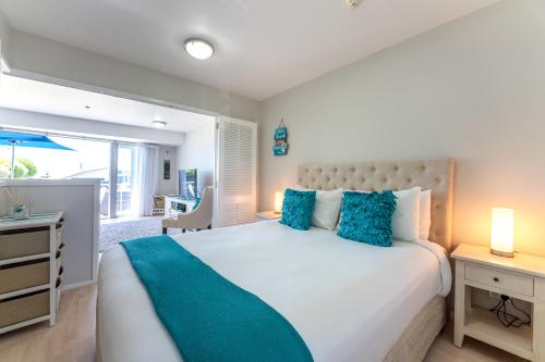 a bedroom with a large white bed with blue pillows at Oneroa Bay Villas in Oneroa