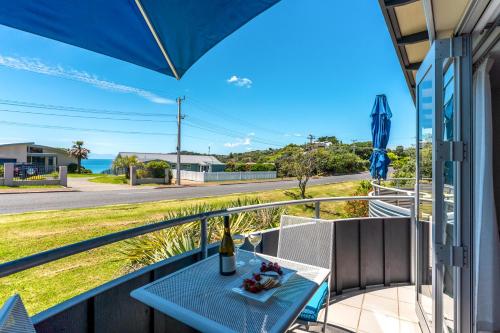 a balcony with a table and a bottle of wine at Oneroa Bay Villas in Oneroa