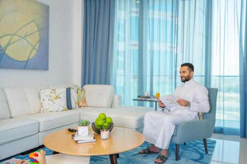a man sitting in a chair reading a paper in a living room at Springfield Suites in Seef